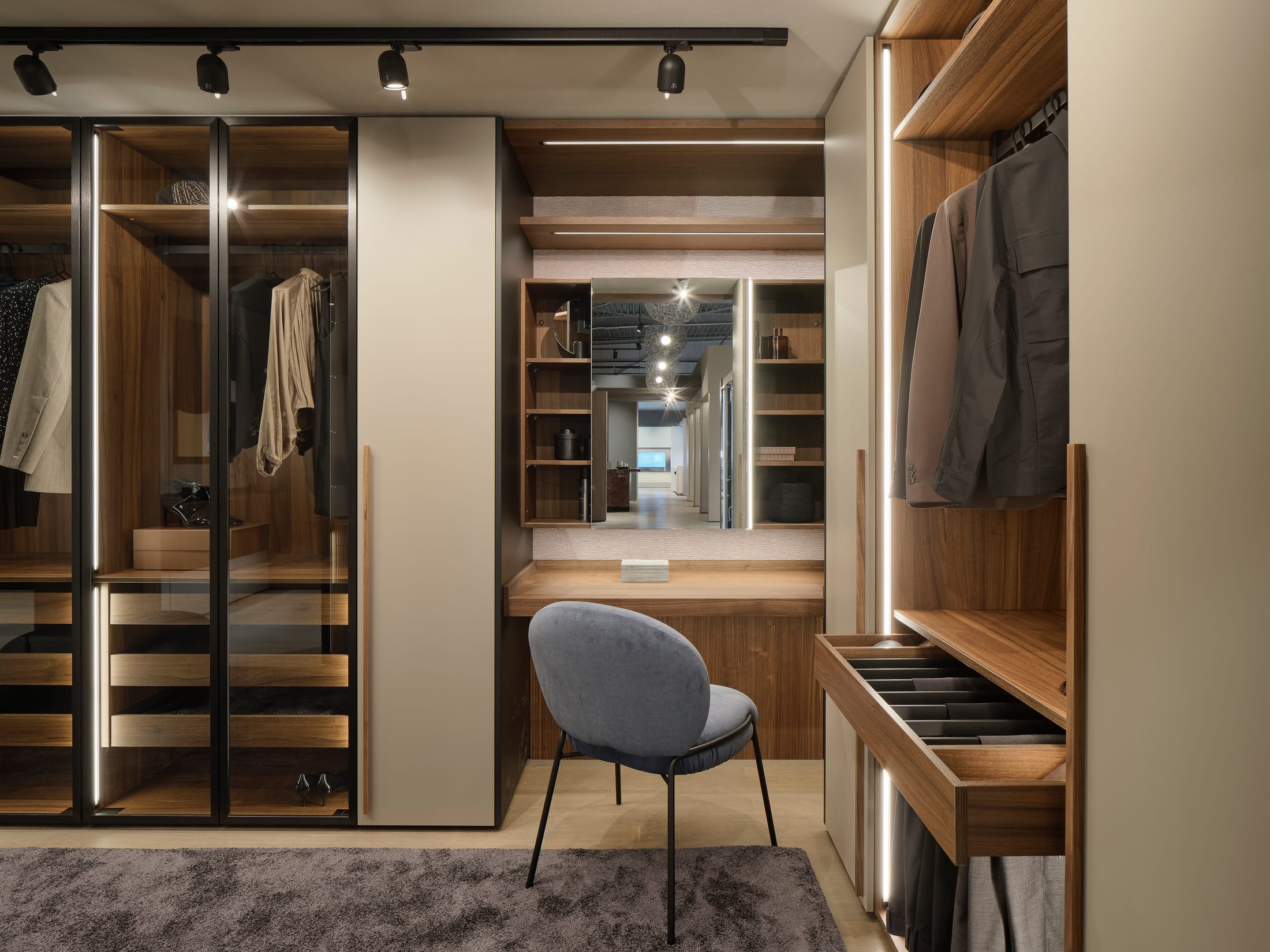 Walk-in closet with bronze glass wardrobes and a dressing table