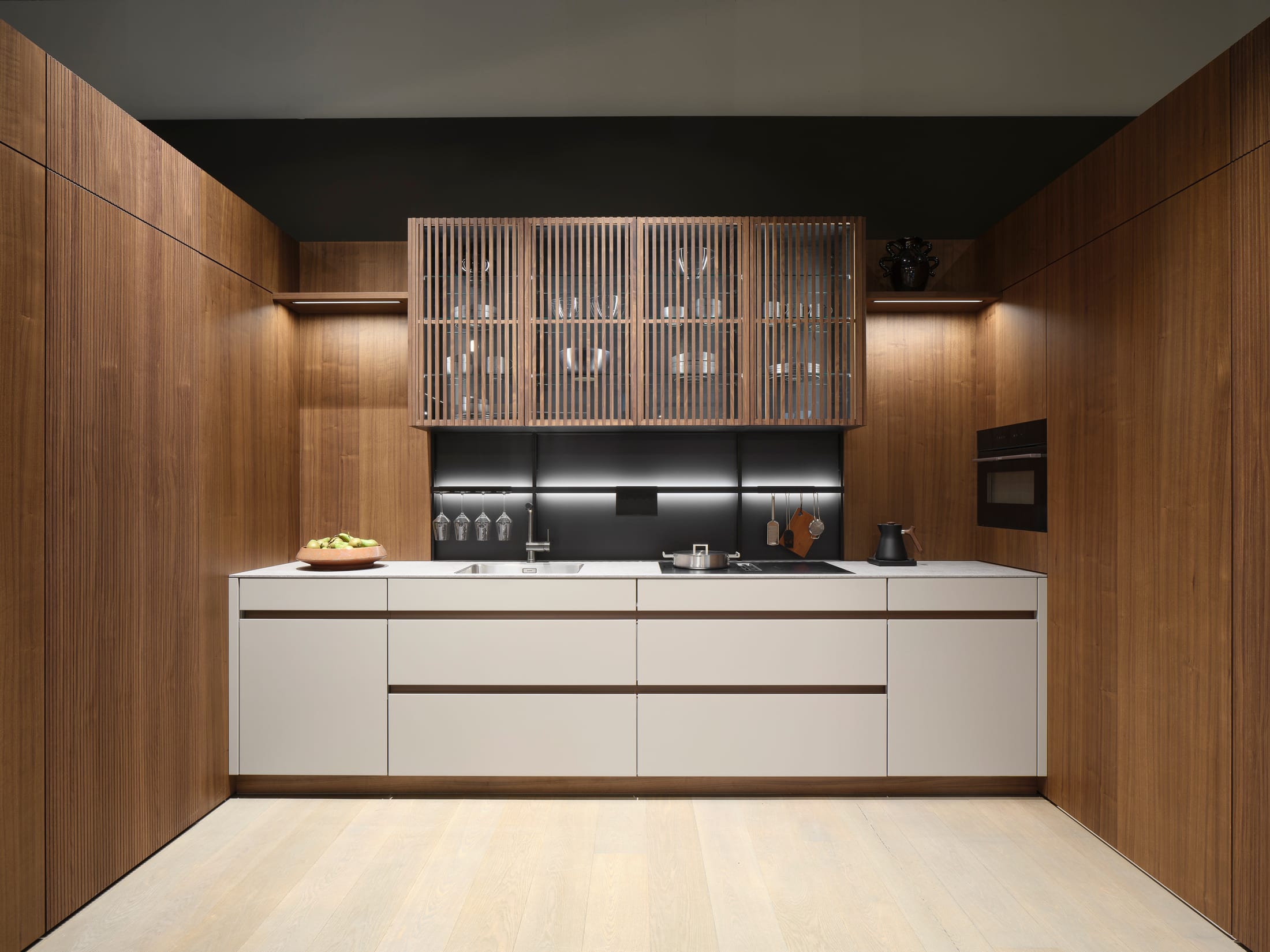 Walnut kitchen with fluted glass wall cabinets and a pale stone counter