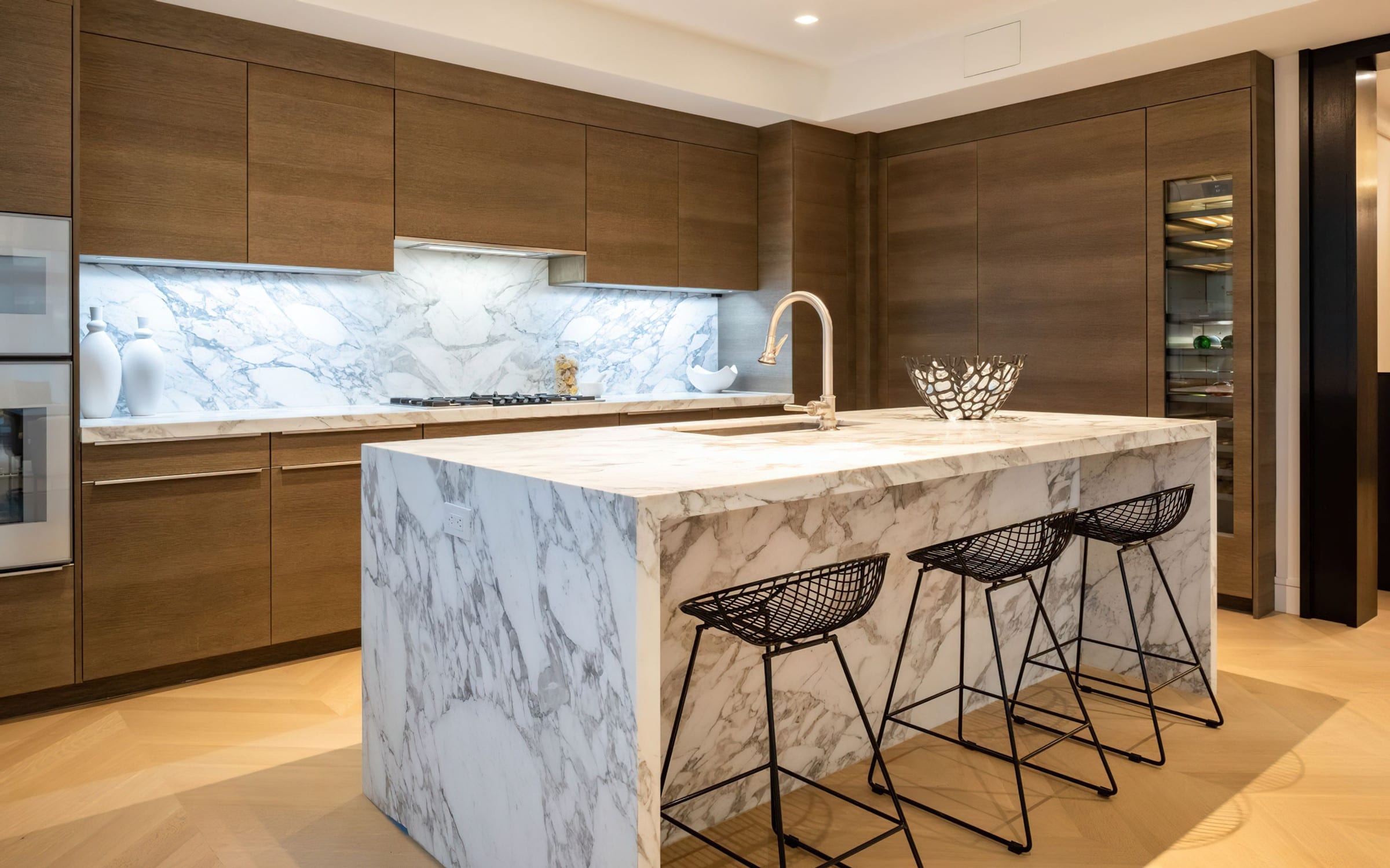 Marble waterfall island and wood-textured cabinets