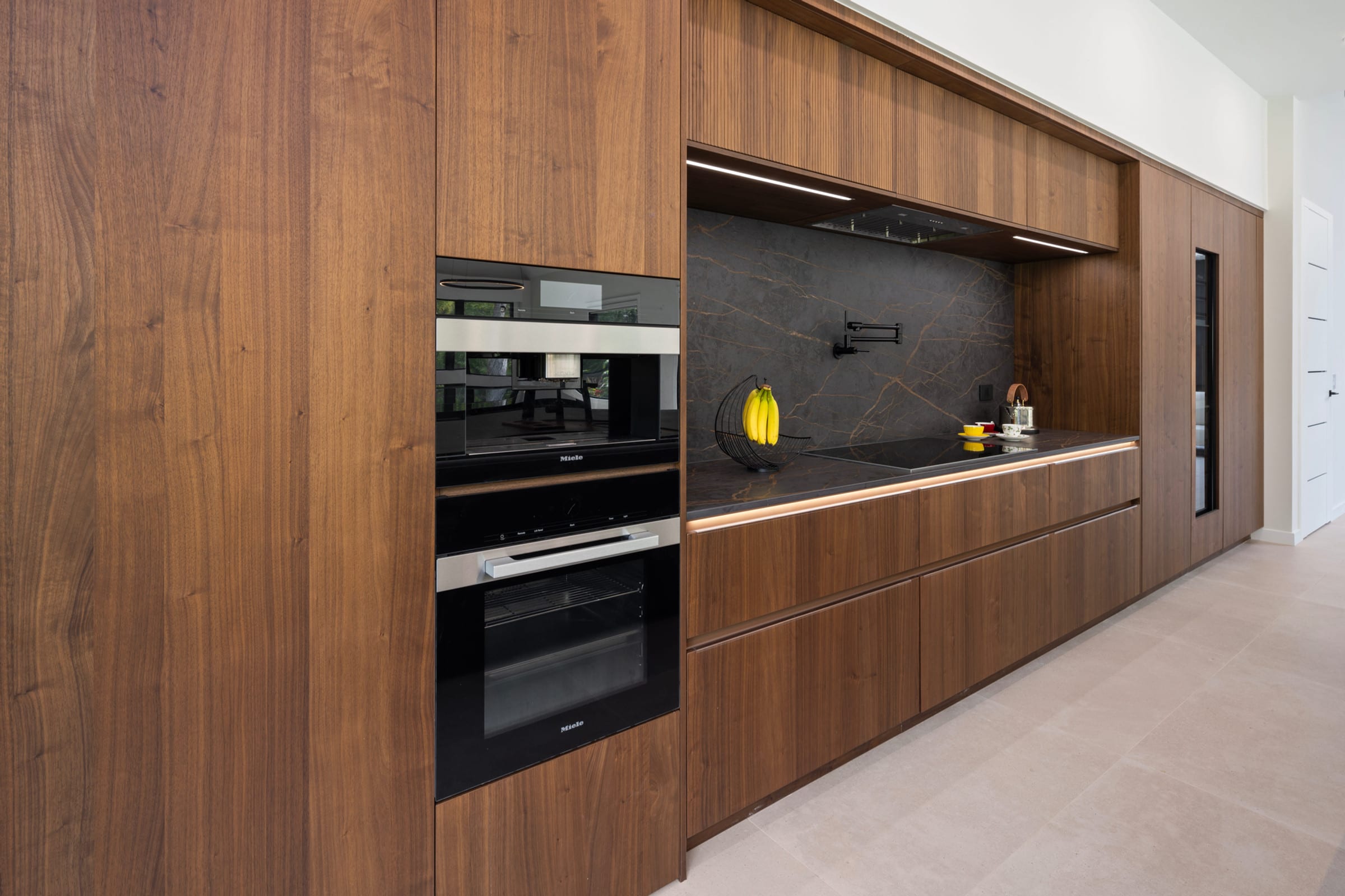 Tall walnut wall with ovens and hidden pantry door