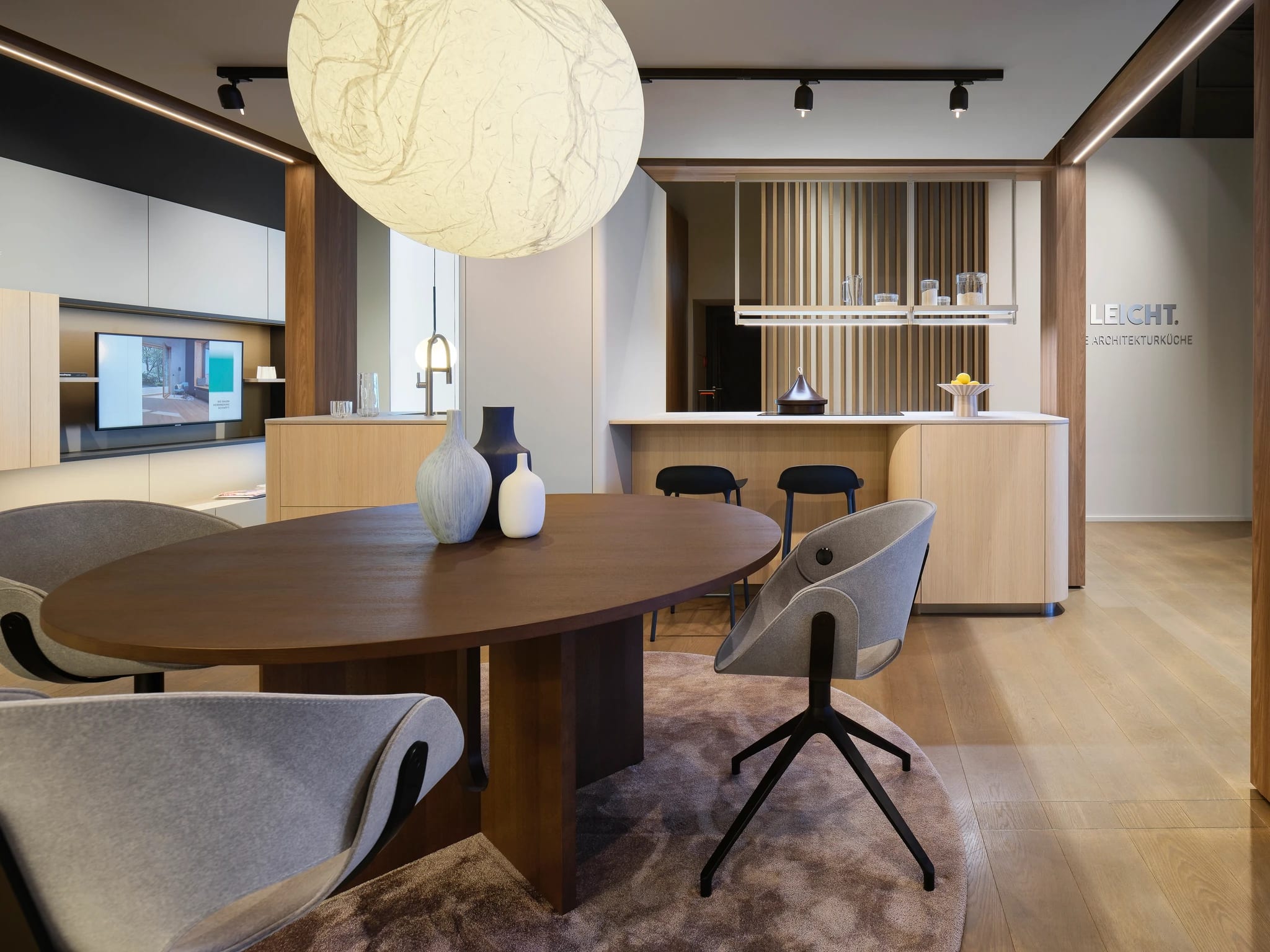 Oval walnut dining table in front of a rounded oak island